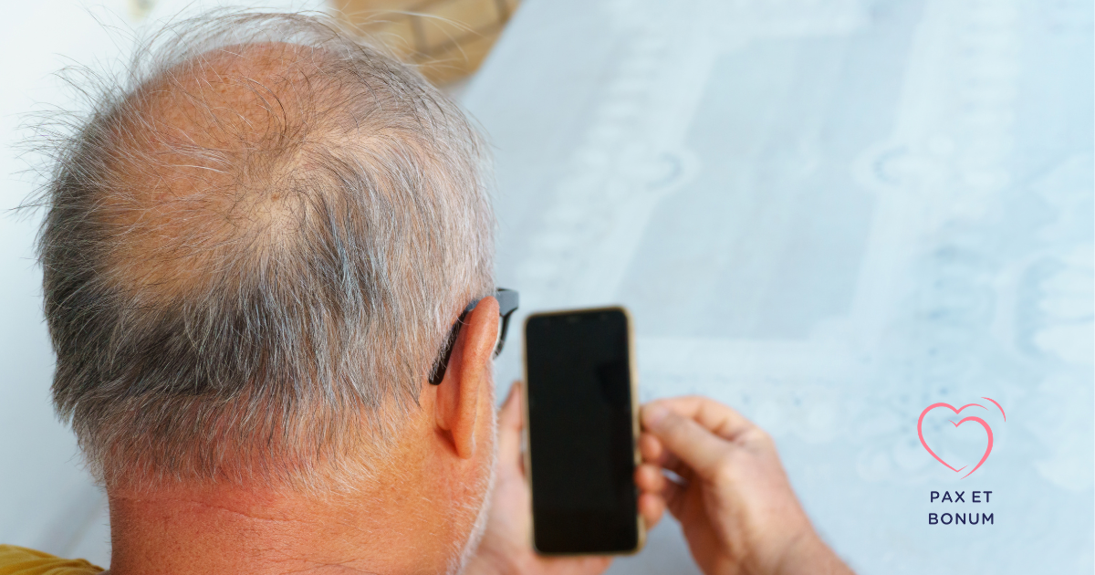 Starszy mężczyzna trzyma telefon przy uchu, widziany zza pleców