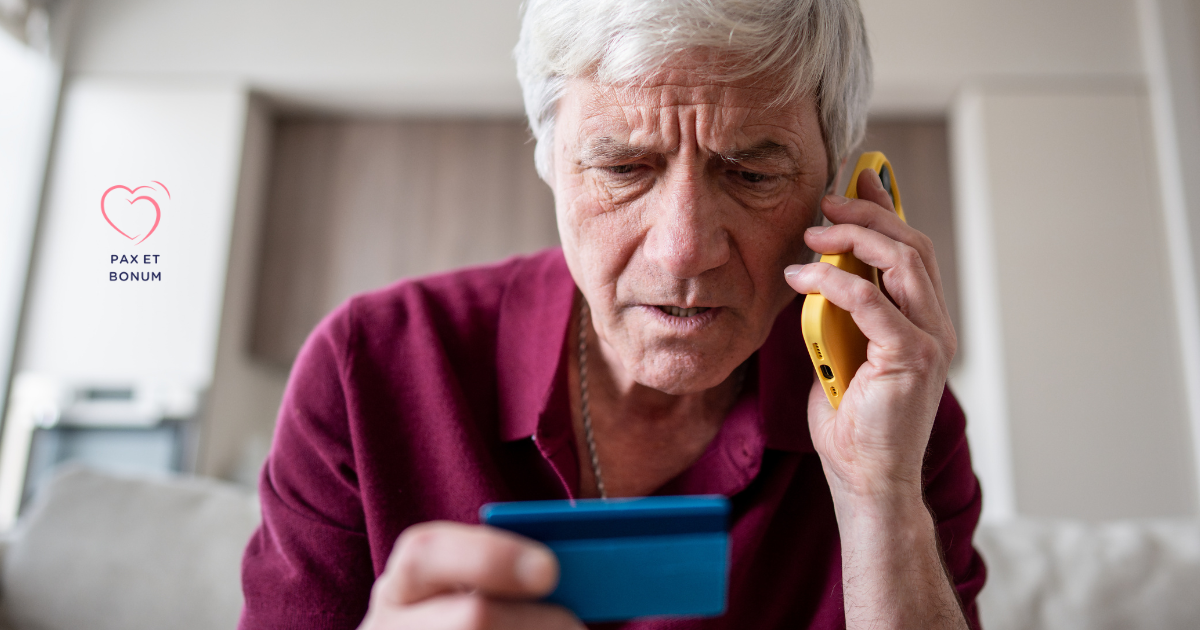 Zaniepokojony starszy mężczyzna rozmawia przez telefon, trzymając kartę płatniczą