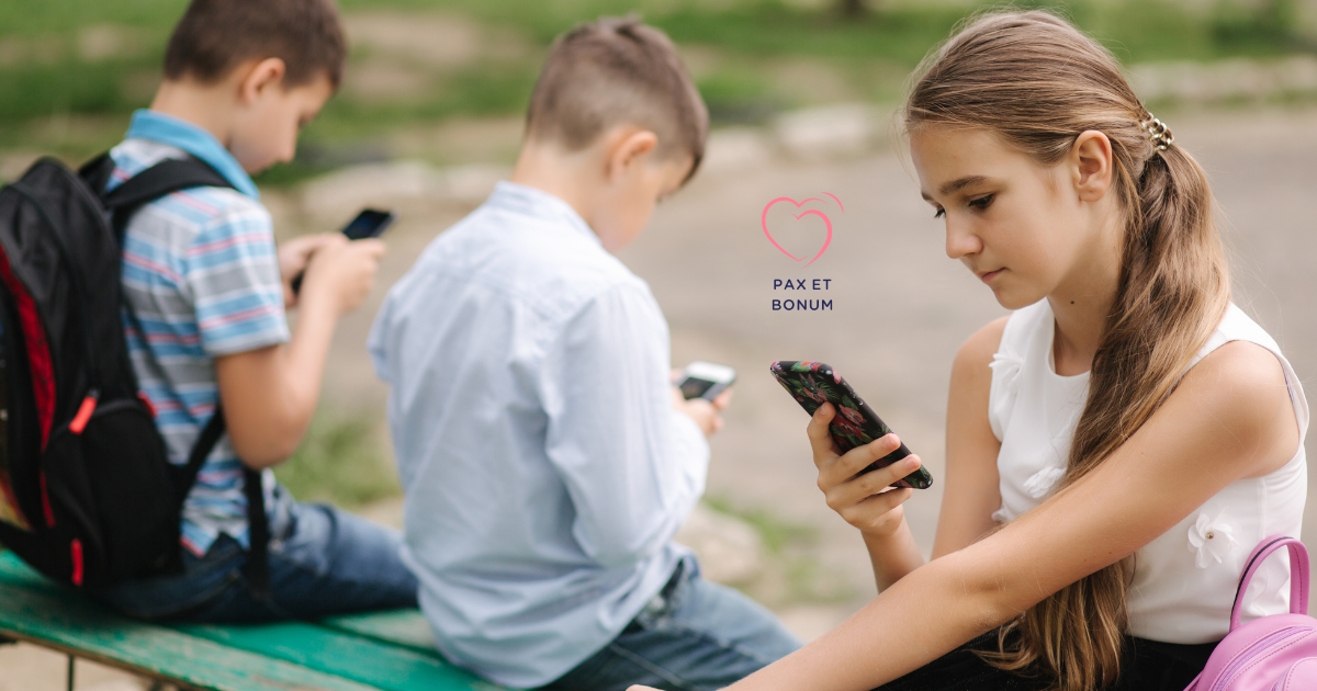 Troje dzieci siedzi na ławce, każde patrzy we własny telefon