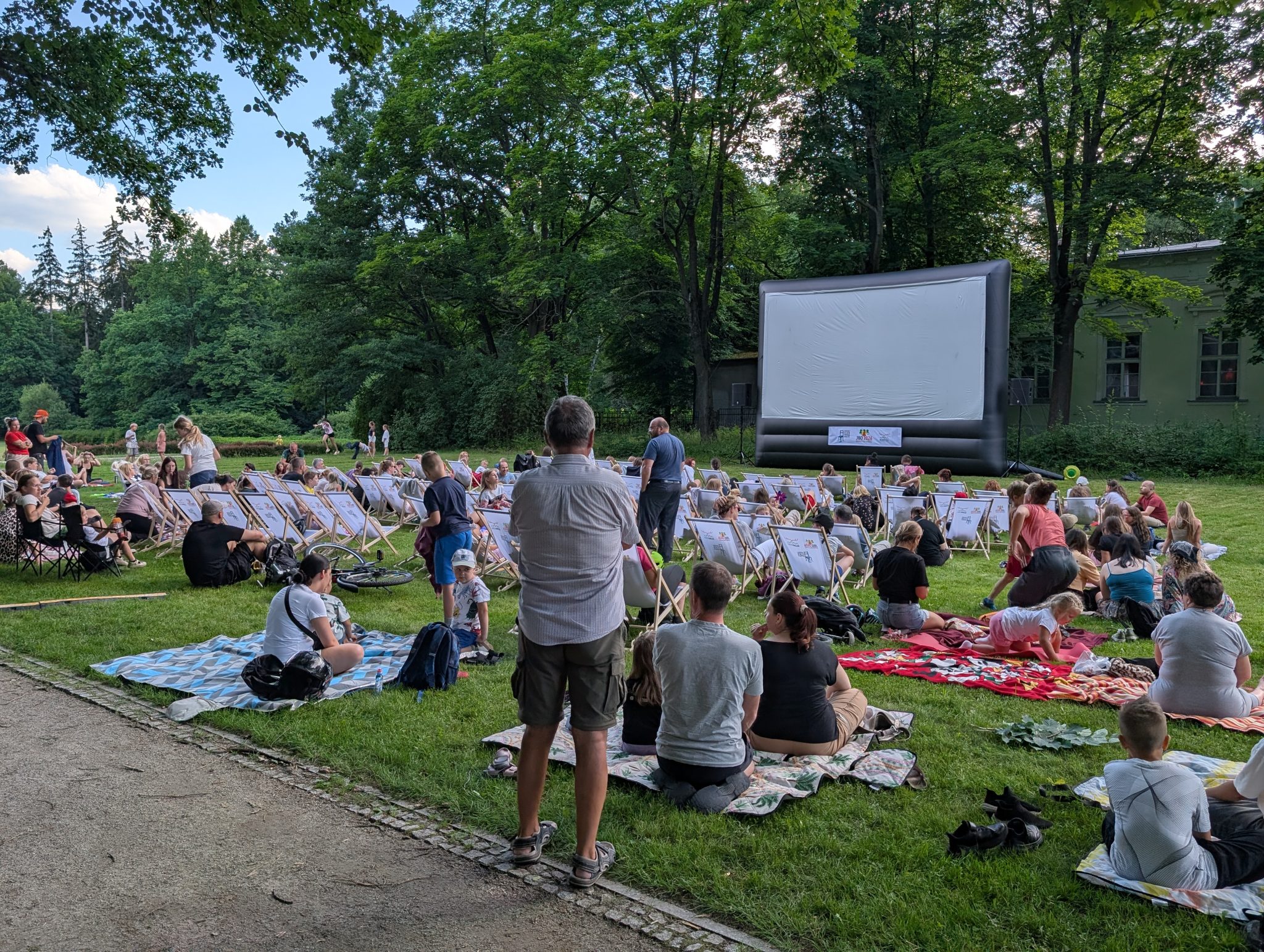 Wieczorny seans kina plenerowego w Cieplicach, ludzie na kocach i leżakach